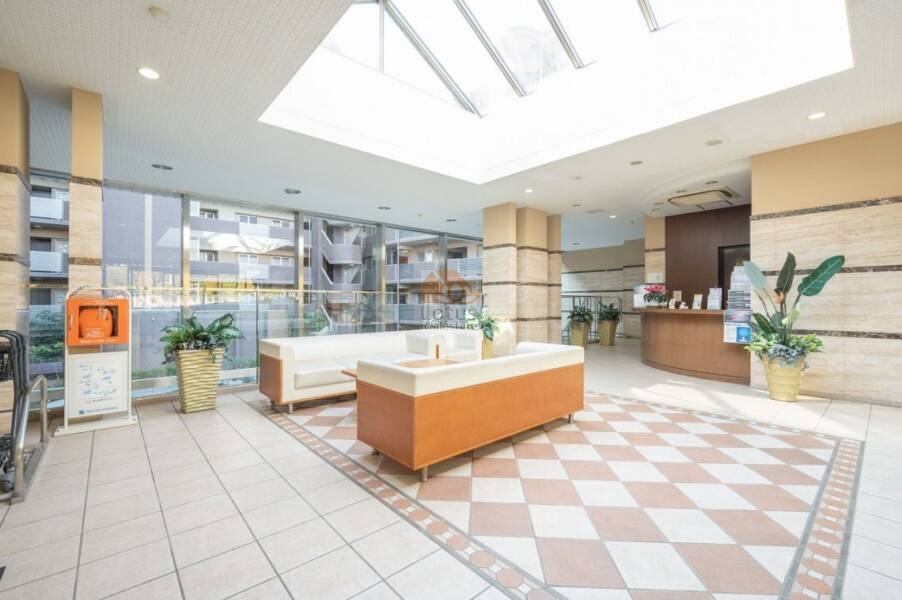 ライオンズマンション馬込マークヒルズエントランスホール１｜吹き抜けの天井と天窓からの自然光が差し込む、明るく気品あるエントランスホール。受付カウンターも設置され、日常の安心と快適性を支えます。